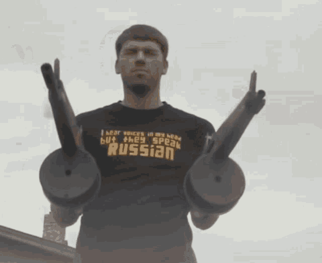 a man wearing a shirt that says russian is holding a pair of guns