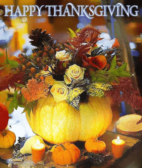 a pumpkin filled with flowers and candles with the words happy thanksgiving above it