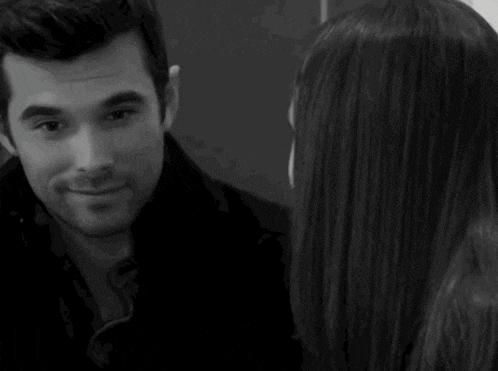 a man and a woman are looking at each other in a black and white photo . the woman is crying .