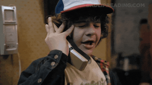 a young boy is talking on a phone with the website badeipreading.com visible in the background