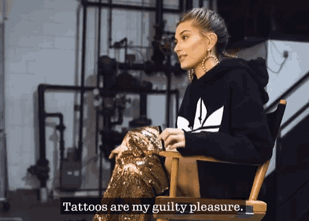 a woman in a black adidas sweatshirt sits in a directors chair