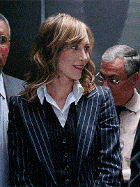 a woman in a striped suit is standing in an elevator with two men