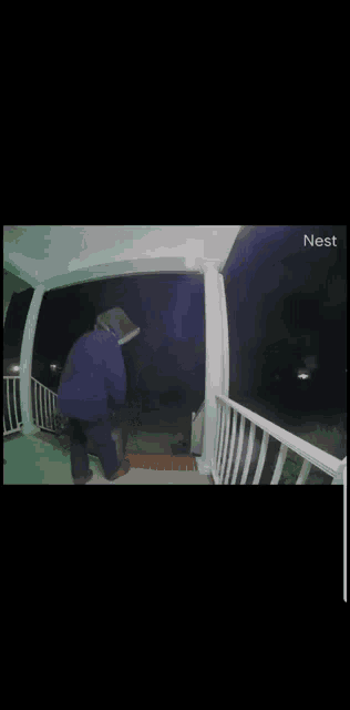 a man in a blue jacket is standing on a porch at night .