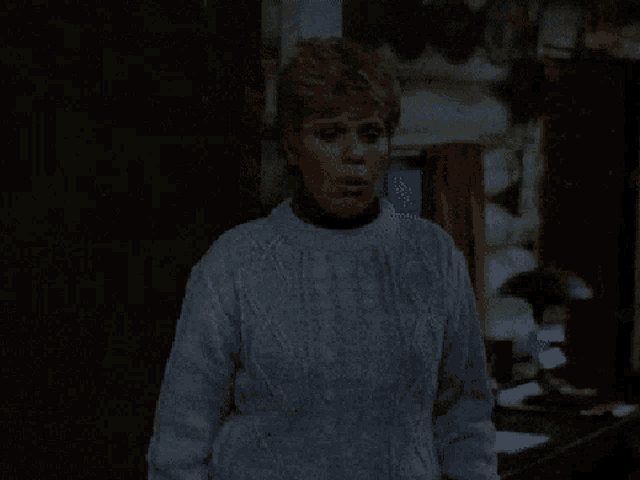 a woman in a white sweater stands in front of a wooden wall