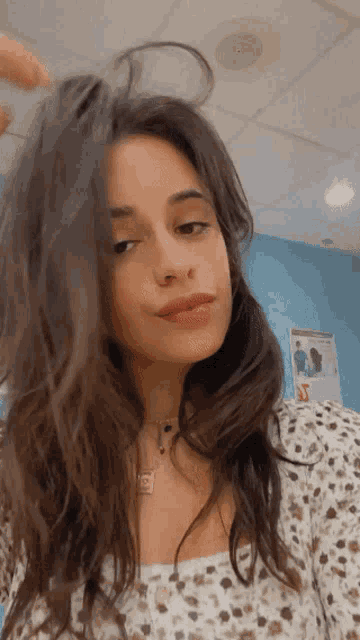 a woman in a polka dot shirt is holding her hair up