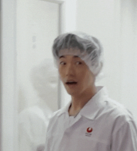 a man wearing a plastic cap and a white shirt with a red circle on it