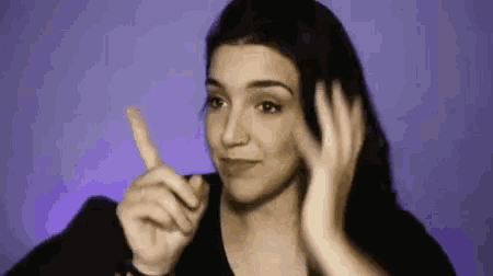 a woman is making a funny face and pointing her finger at something .