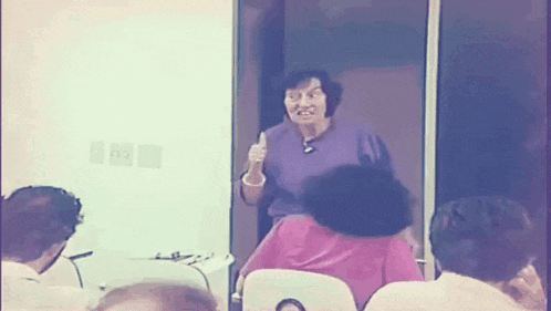 a woman in a purple shirt is giving a presentation