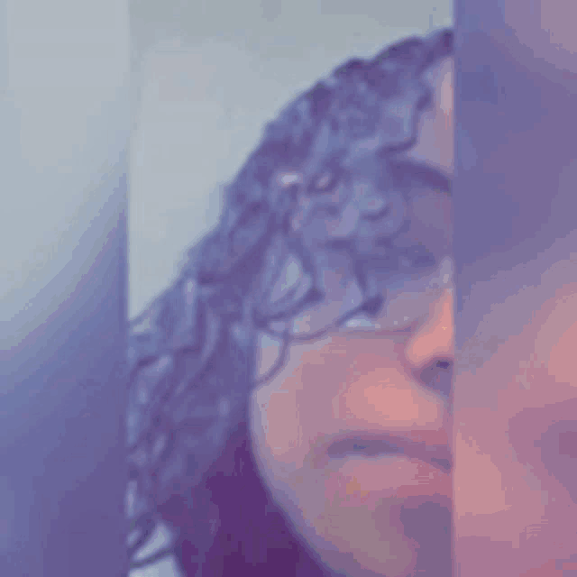 a close up of a person 's face with curly hair and glasses