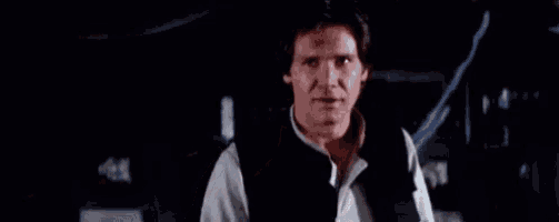 han solo from star wars is standing in a dark room and looking at the camera .