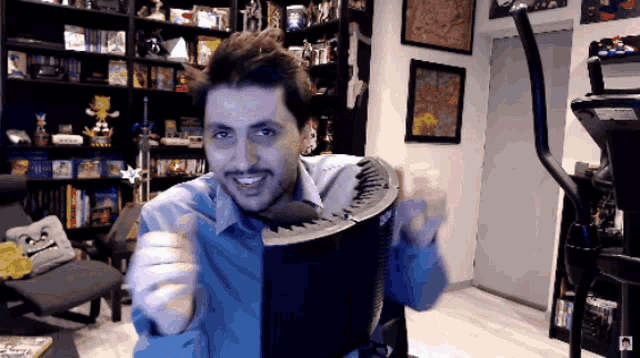 a man in a blue shirt is smiling and holding a black object