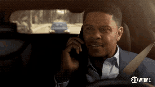 a man in a car talking on a cell phone with showtime written on the bottom