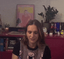 a woman wearing a teddy bear shirt is sitting in front of a painting