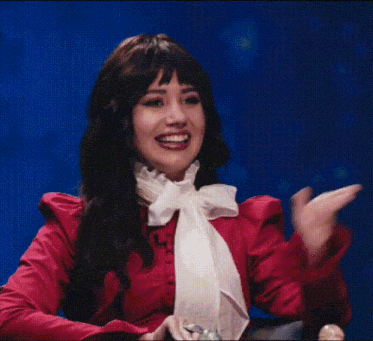 a woman wearing a red shirt and a white bow tie is sitting in a chair .