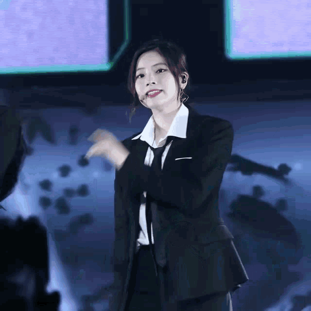 a woman wearing a suit and tie is dancing on stage