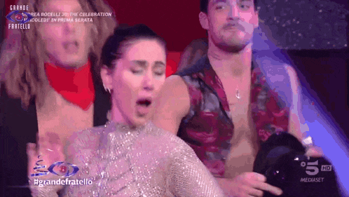 a group of people are dancing on a stage with the words grande fratello on the bottom