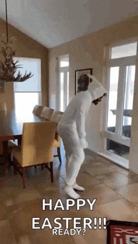 a man in a white bunny suit is dancing in a living room .