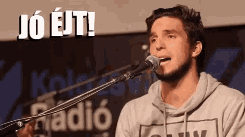 a man is singing into a microphone while holding a guitar in his hand .