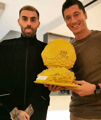 two men holding a fifa ballon d' or trophy