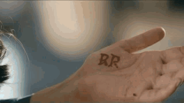 a close up of a person 's hand with the letters rr written on it