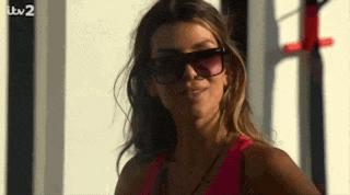 a woman wearing sunglasses and a pink tank top is looking at the camera .