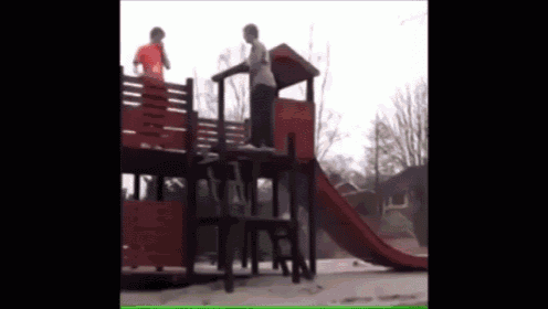 two children are playing on a slide in a park
