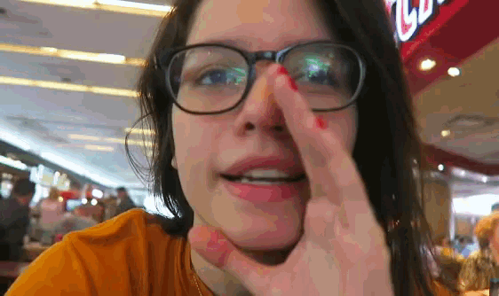 a woman wearing glasses is covering her nose with her hand