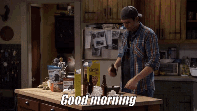 a man in a plaid shirt is standing in a kitchen with a box of cheerios on the counter