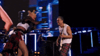 a man is playing a guitar and a woman is dancing on a stage