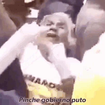 a man in a yellow shirt is being punched in the face by a group of people .