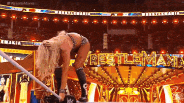a woman is kneeling on a rope in a stadium .