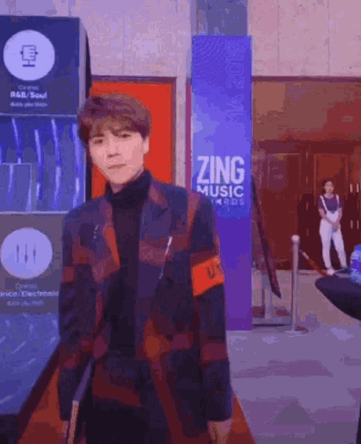 a man stands in front of a purple sign that says zing music awards