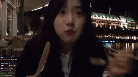 a girl is eating a piece of meat with a fork in front of a building