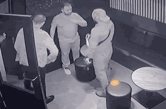 a group of men are standing in a room with a table
