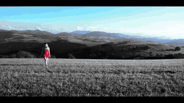 a woman in a red dress is walking through a field