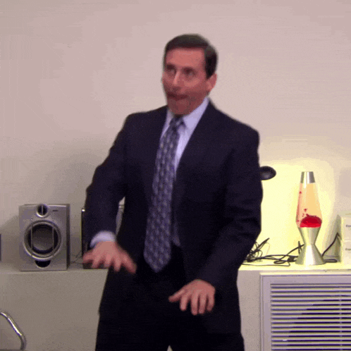 a man in a suit and tie is dancing in front of speakers