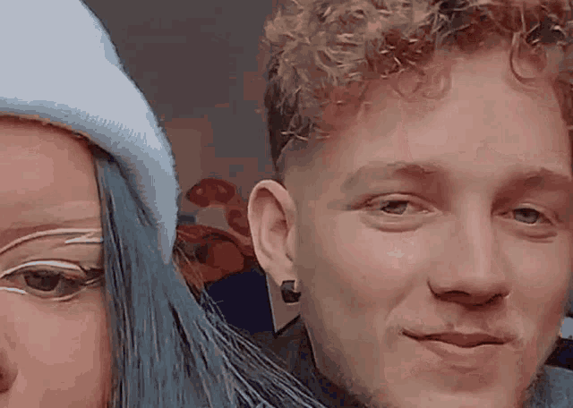 a man and woman are posing for a picture and the woman has blue hair