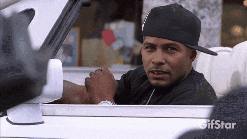 a man in a black hat is sitting in a car with gifstar written on the bottom right