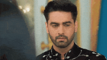 a man with a beard is standing in front of a mirror and looking at himself in the mirror .