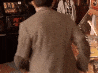 a man in a suit is standing in front of a slot machine .