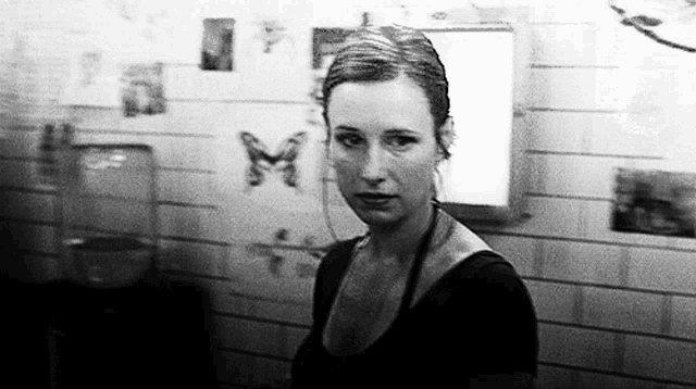 a black and white photo of a woman in front of a wall with butterflies