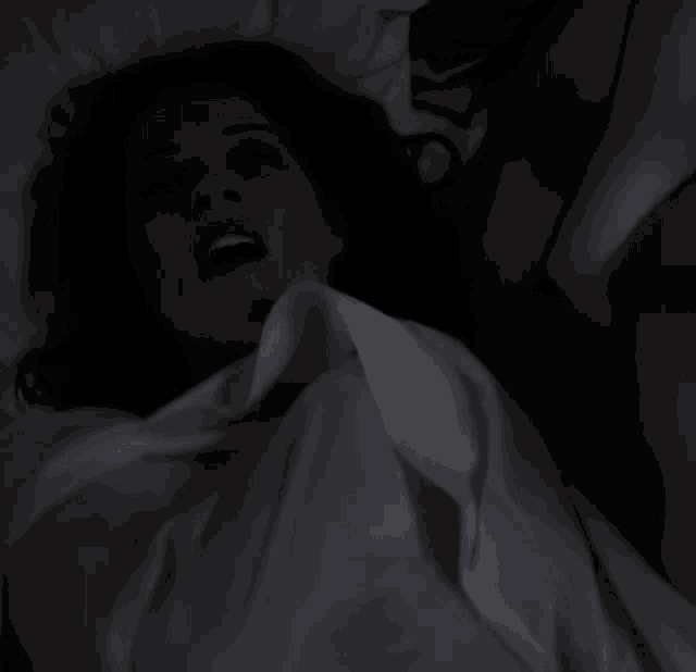 a woman laying in a bed with her mouth open