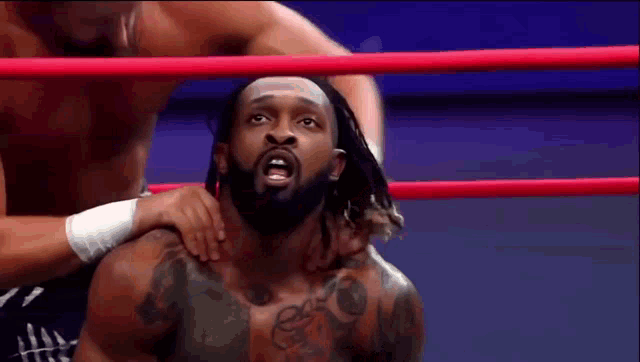 a man with dreadlocks is wrestling in a ring with another man .