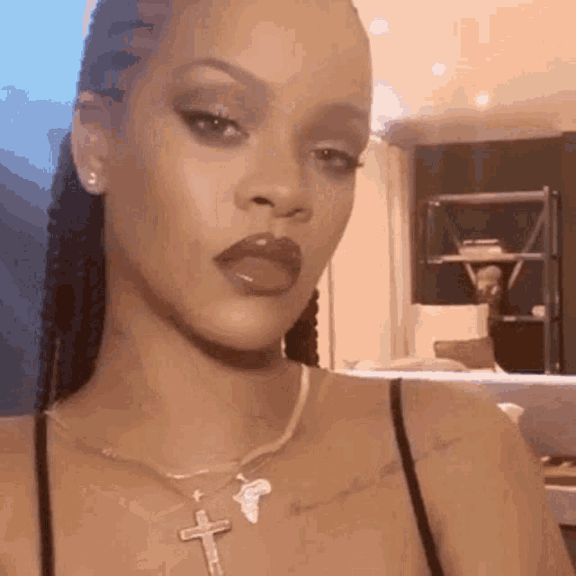 a close up of a woman wearing a cross necklace and braids .