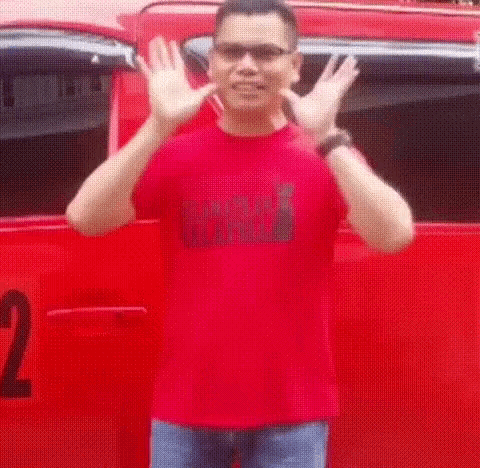 a man in a red shirt and sunglasses is standing in front of a red van .