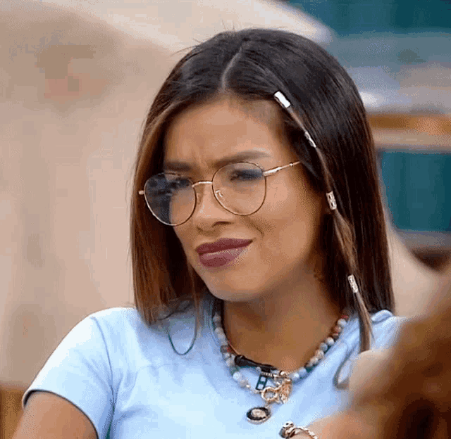 a woman wearing glasses and a necklace with the letter b on it