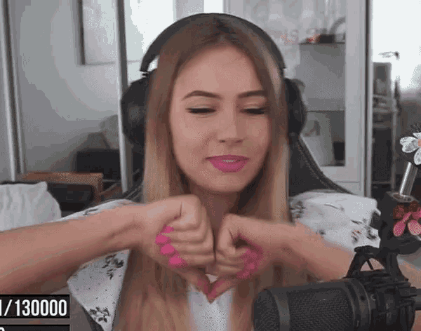 a woman is making a heart shape with her hands in front of a microphone