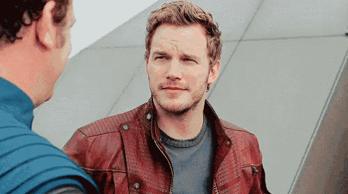 a man wearing a red leather jacket is standing next to another man .