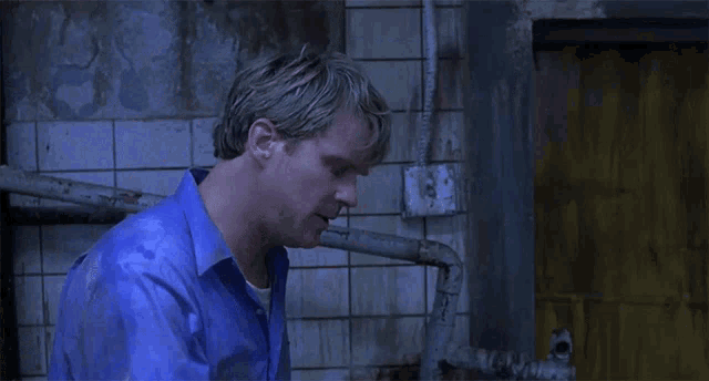 a man in a blue shirt holds his head in pain