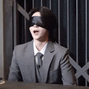 a man in a suit and tie has his eyes covered